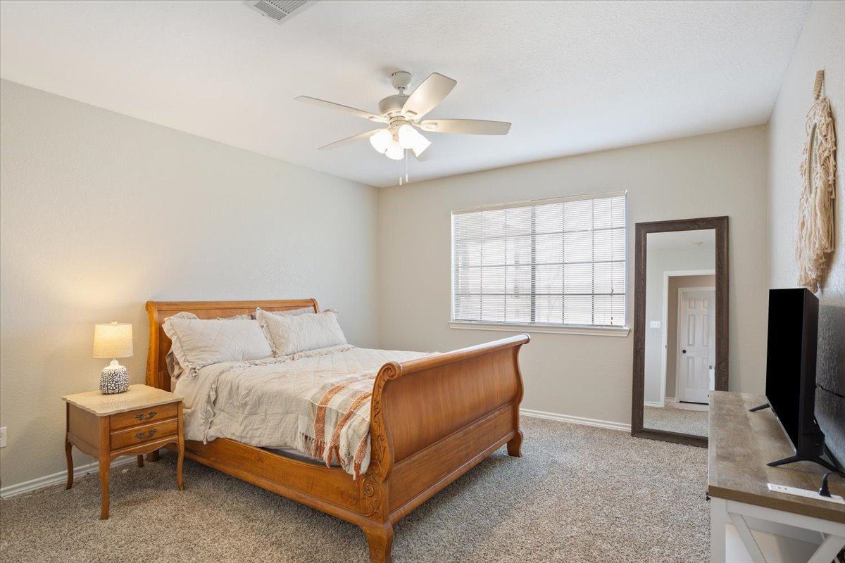 8600 Five Wells Road Rogers, TX 76569 - Photo 21 of 40 a bedroom with a bed and a flat tv screen on a dresser