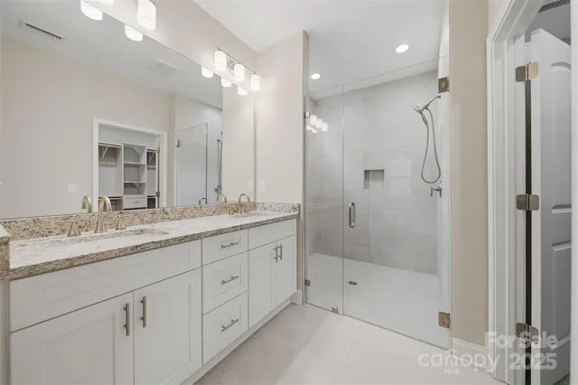 a bathroom with a granite countertop sink two mirror and shower