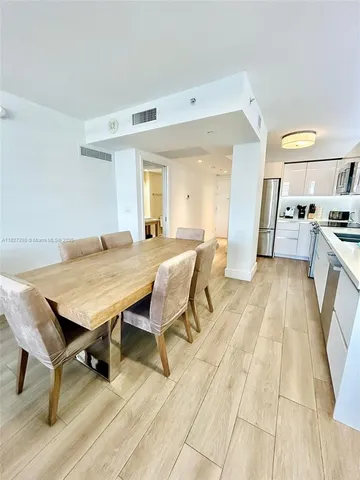 a living room with a table chairs and a kitchen view