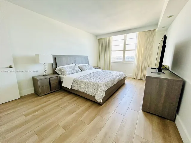a bedroom with a bed flat screen tv and window