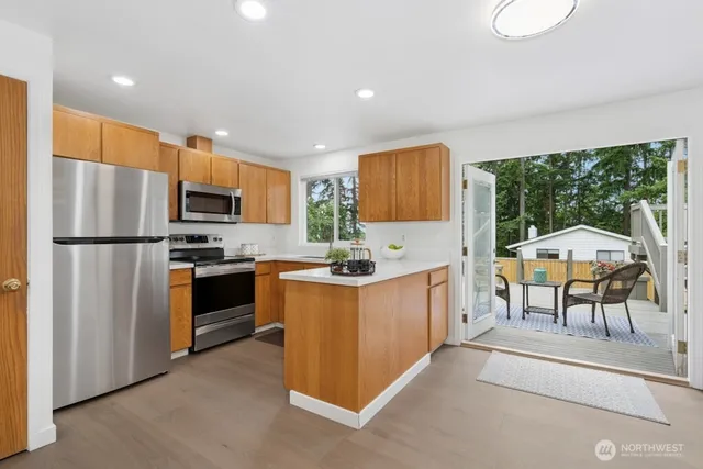 a kitchen with stainless steel appliances kitchen island granite countertop a refrigerator a stove top oven a sink and dishwasher with wooden floor