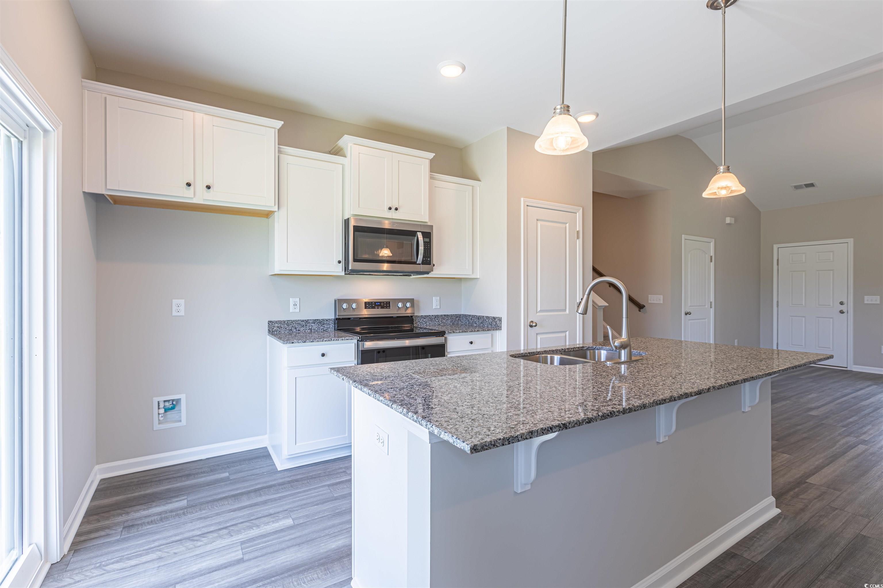 Kitchen with sink, white cabinetry, appliances wit