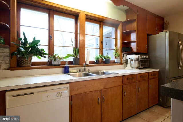 a kitchen with stainless steel appliances a sink a refrigerator and a window
