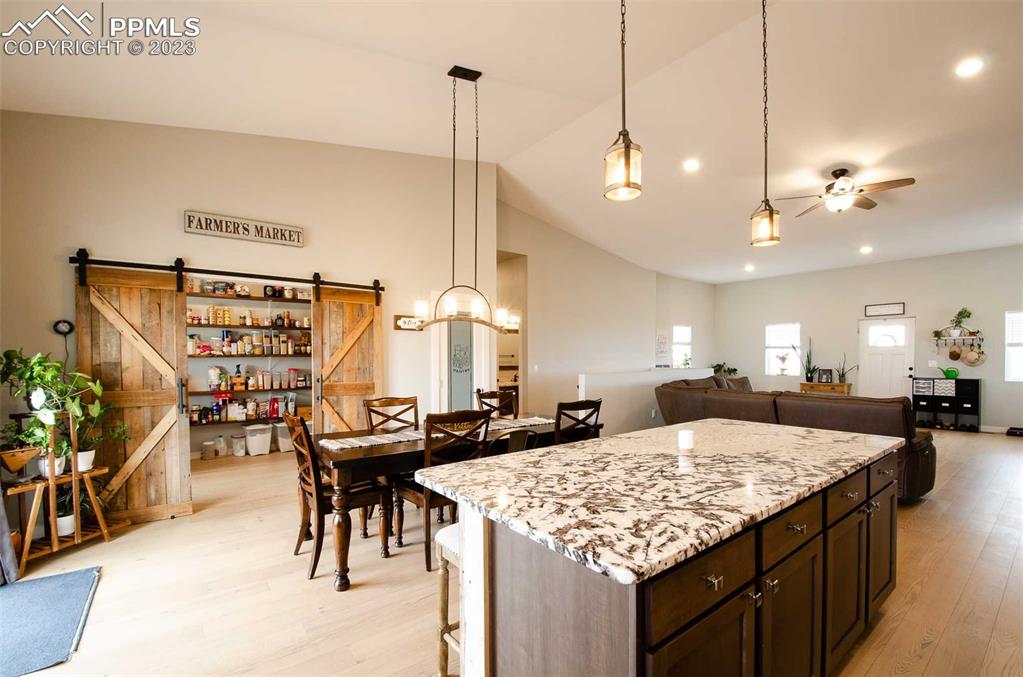 16750 Rabbit Track Trail Colorado Springs, CO 80930 - Photo 9 of 50 a large kitchen with kitchen island a large island a sink dishwasher a dining table and chairs with wooden floor