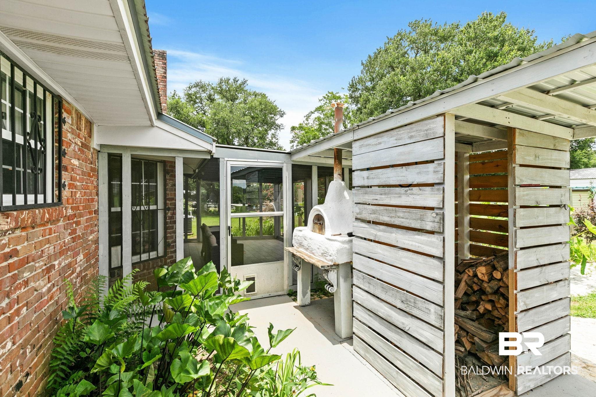 3791 Robinsonville Road Atmore, AL 36502 - Photo 42 of 55 Outdoor pizza oven with integrated wood storage, screened patio, brick facade, and established landscaping