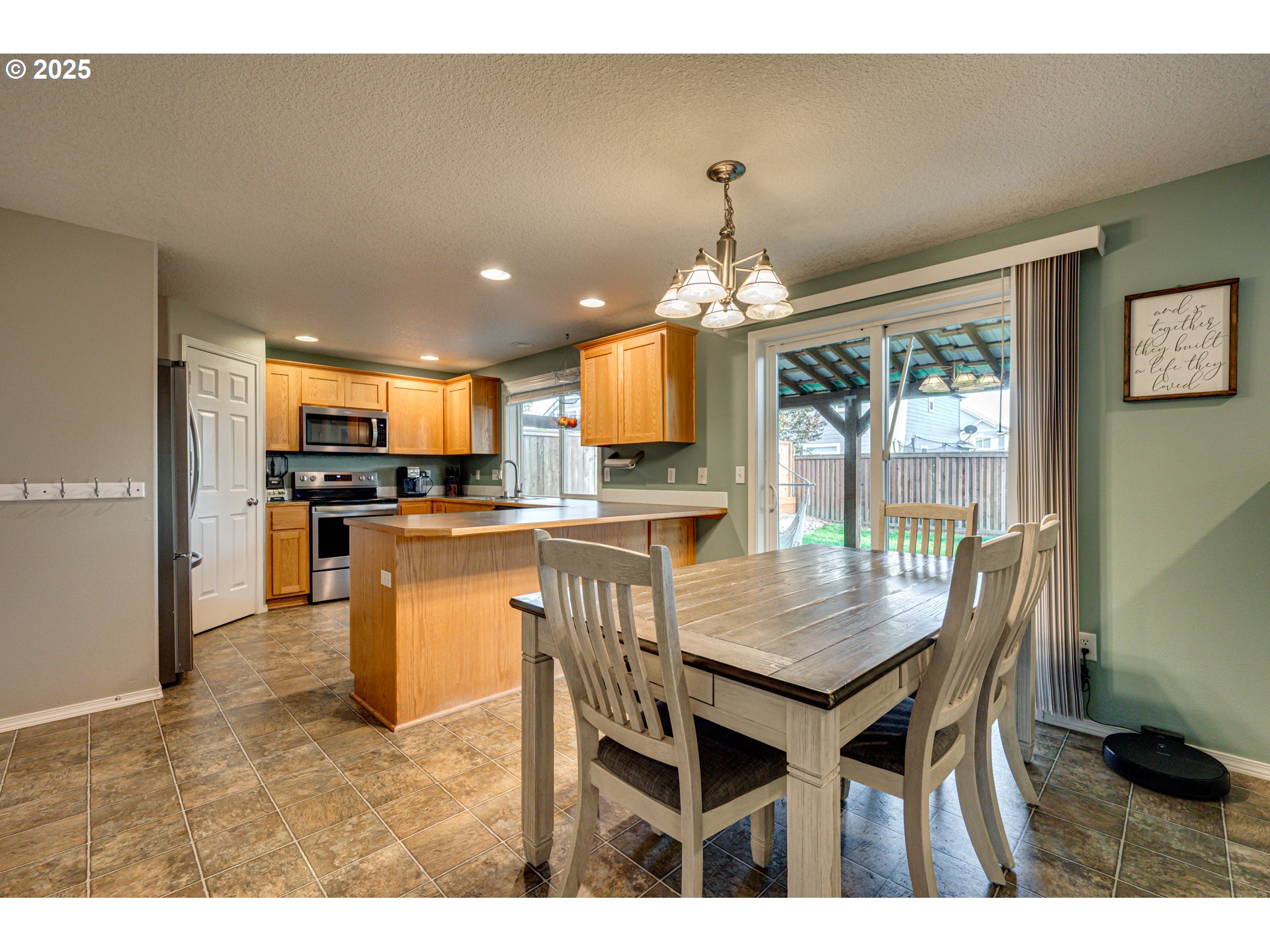 1825 North 9th Way Ridgefield, WA 98642 - Photo 3 of 30 a kitchen with stainless steel appliances kitchen island granite countertop a table chairs and a refrigerator