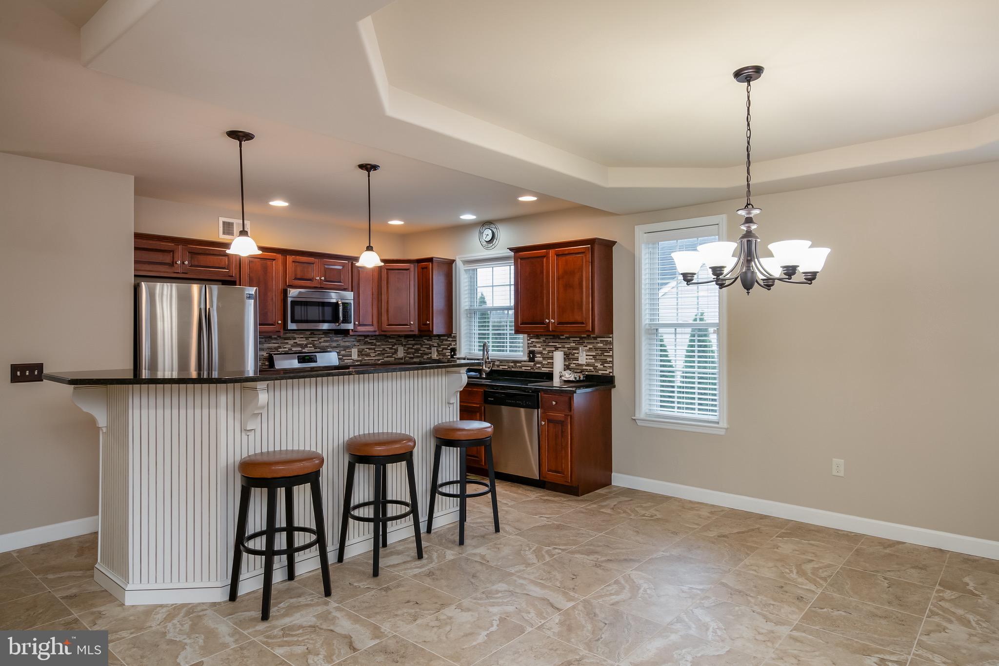 654 Ebersole Road Reading, PA 19605 - Photo 9 of 27 a kitchen with stainless steel appliances granite countertop a refrigerator a stove a sink dishwasher a dining table and chairs with wooden floor