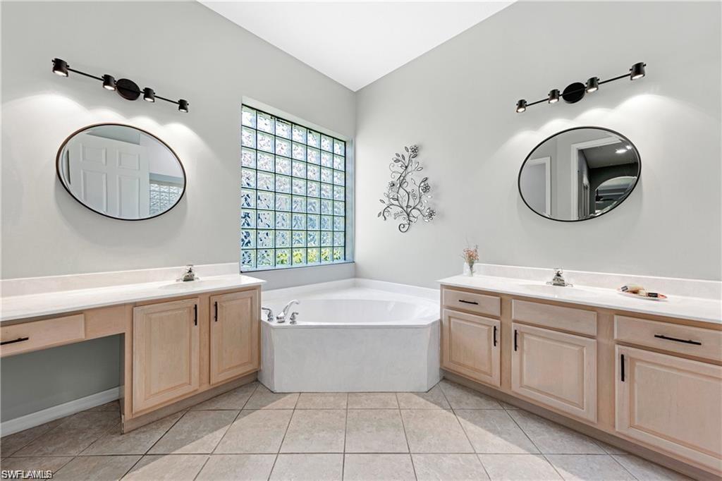 349 Harvard Lane Naples, FL 34104 - Photo 13 of 31 a bathroom with a sink a mirror a bathtub and a window