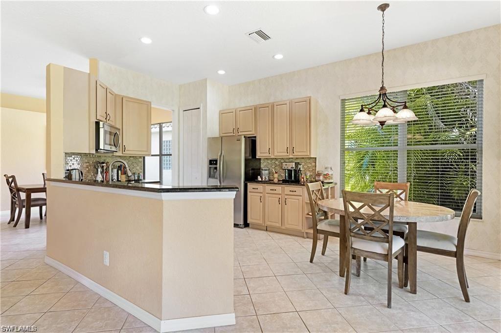 349 Harvard Lane Naples, FL 34104 - Photo 7 of 31 a kitchen with kitchen island granite countertop a stove a table and chairs
