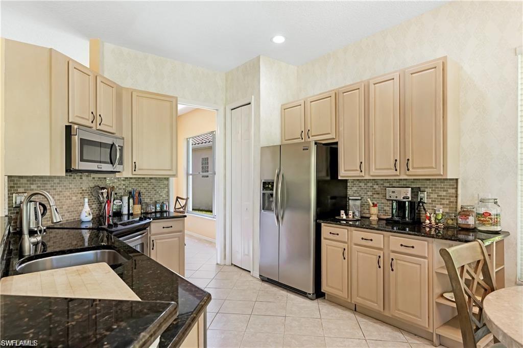 349 Harvard Lane Naples, FL 34104 - Photo 9 of 31 a kitchen with stainless steel appliances granite countertop a sink a stove a refrigerator a counter space and cabinets