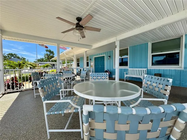 a view of a patio with couches table and chairs under an umbrella with potted plants