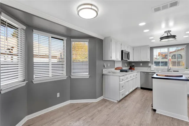 a kitchen with cabinets a window and stainless steel appliances