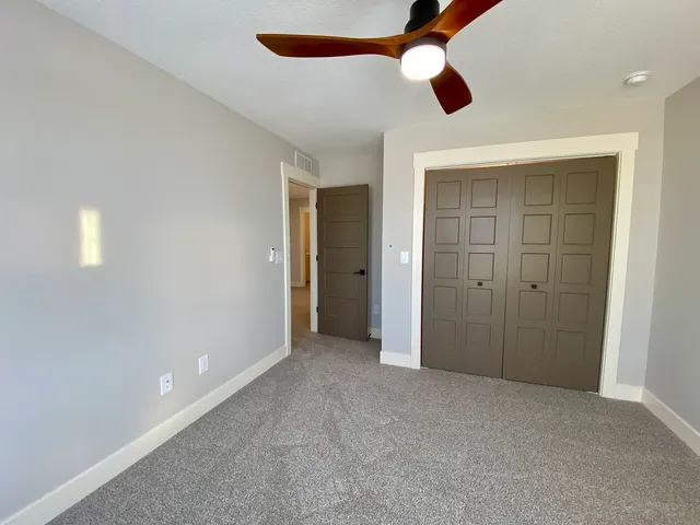 an empty room with closet and a chandelier fan
