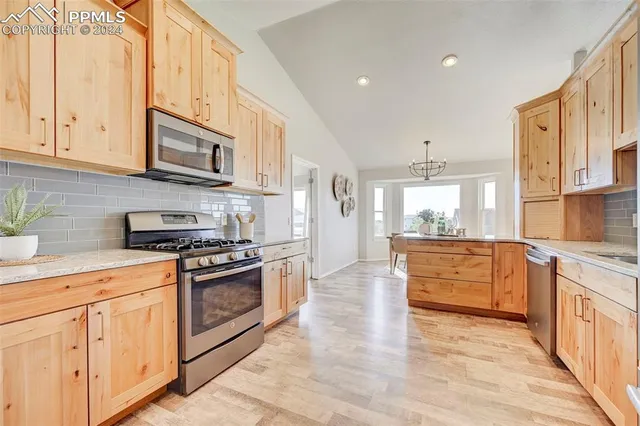 a large kitchen with stainless steel appliances granite countertop a stove a sink and a white cabinets