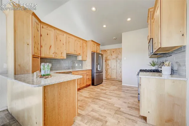 a kitchen with stainless steel appliances granite countertop a refrigerator a stove and white cabinets with wooden floor