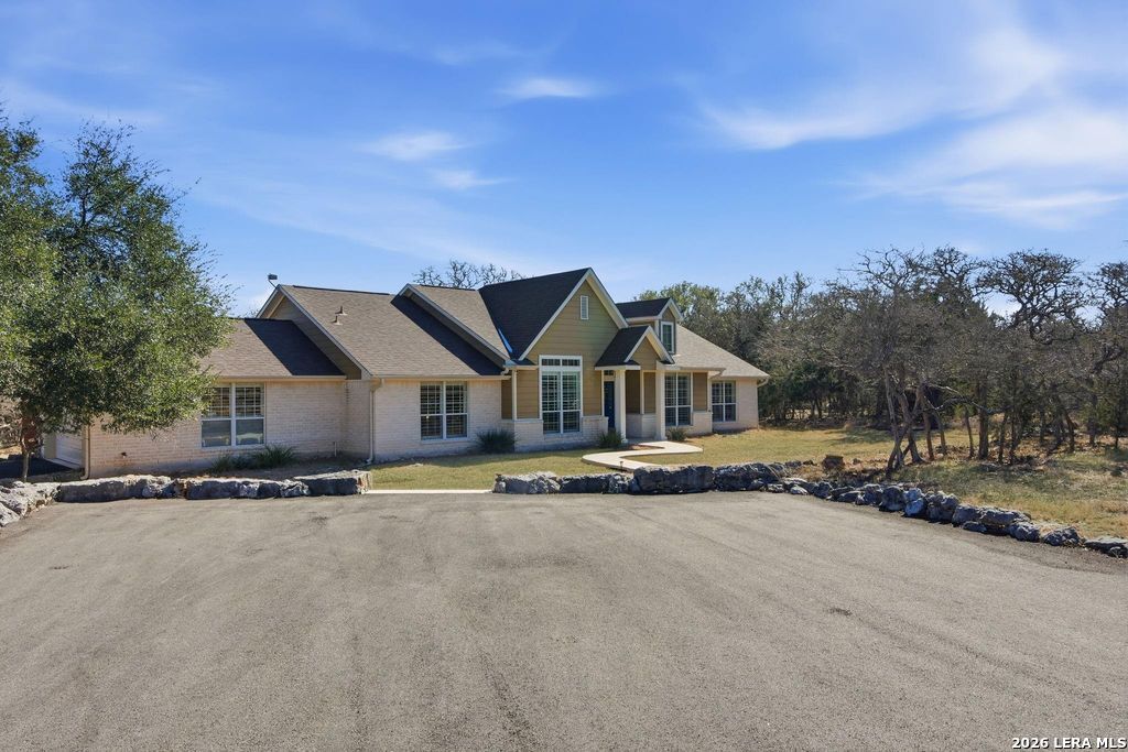 a view of house with a big yard and large trees