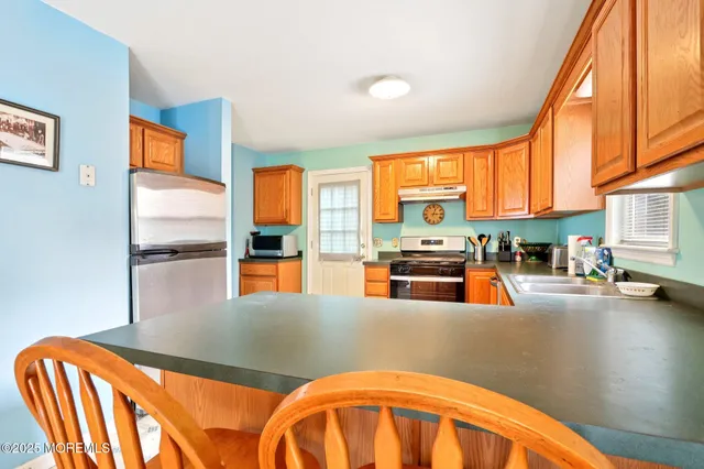 a kitchen with stainless steel appliances wooden floor and a refrigerator