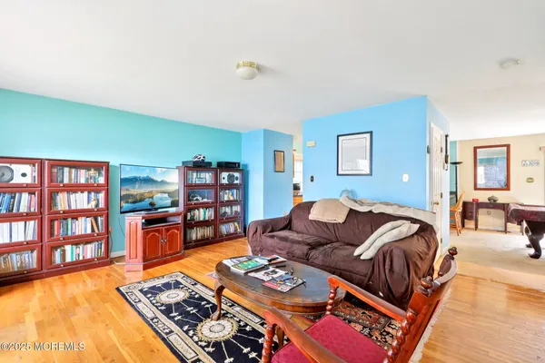 a living room with furniture and a dining table with bookshelf