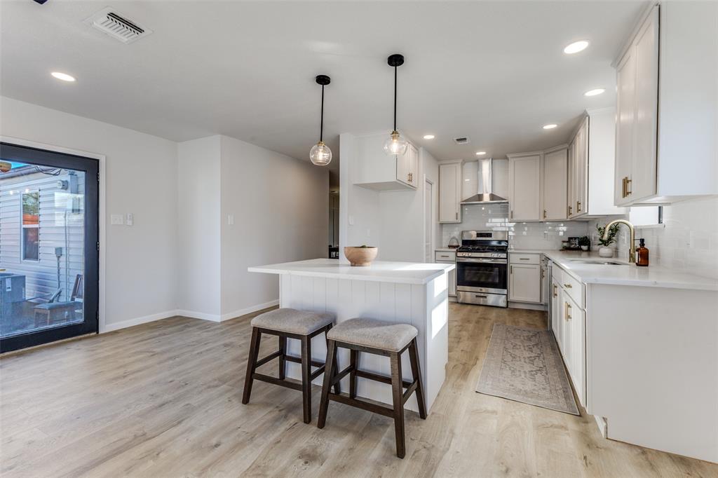 3719 Dutton Drive Dallas, TX 75211 - Photo 11 of 24 a kitchen with stainless steel appliances kitchen island granite countertop a sink a stove a refrigerator and white cabinets with wooden floor
