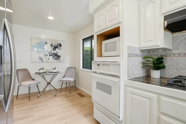 a white kitchen with cabinets and chairs