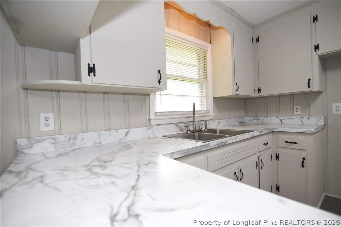1673 Norment Road Lumberton, NC 28360 - Photo 15 of 32 a kitchen with granite countertop a sink and white cabinets
