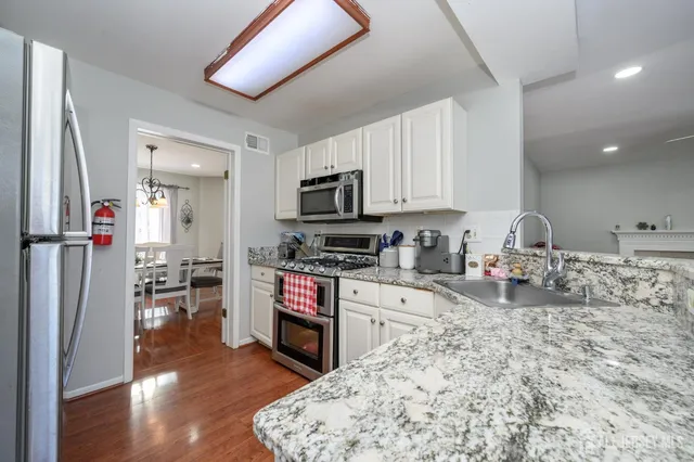 a kitchen with stainless steel appliances granite countertop a stove refrigerator and a sink