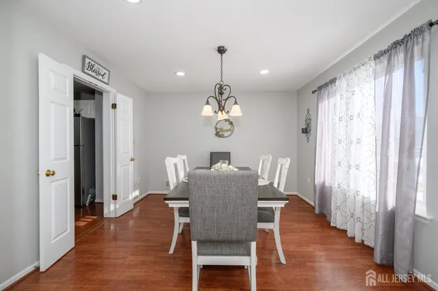 a dining room with wooden floor a chandelier a wooden table and chairs