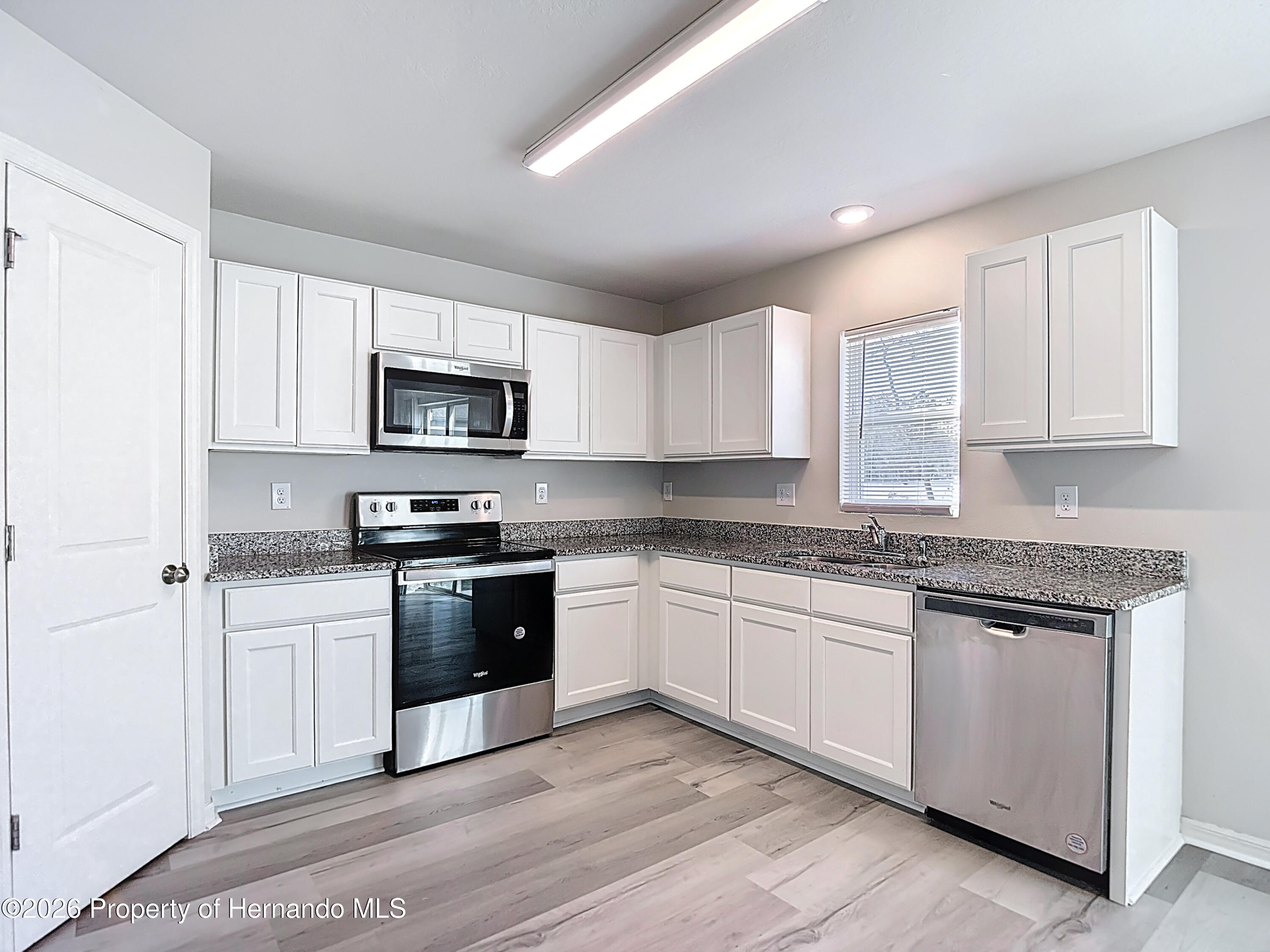 11374 Marcella Avenue Weeki Wachee, FL 34614 - Photo 24 of 70 a kitchen with granite countertop white cabinets and stainless steel appliances