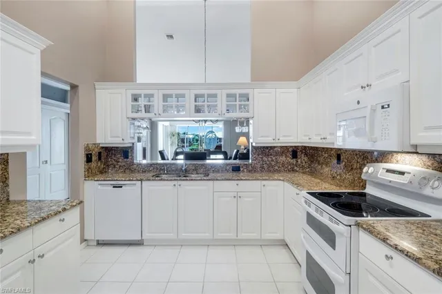 a kitchen with granite countertop white cabinets and white appliances