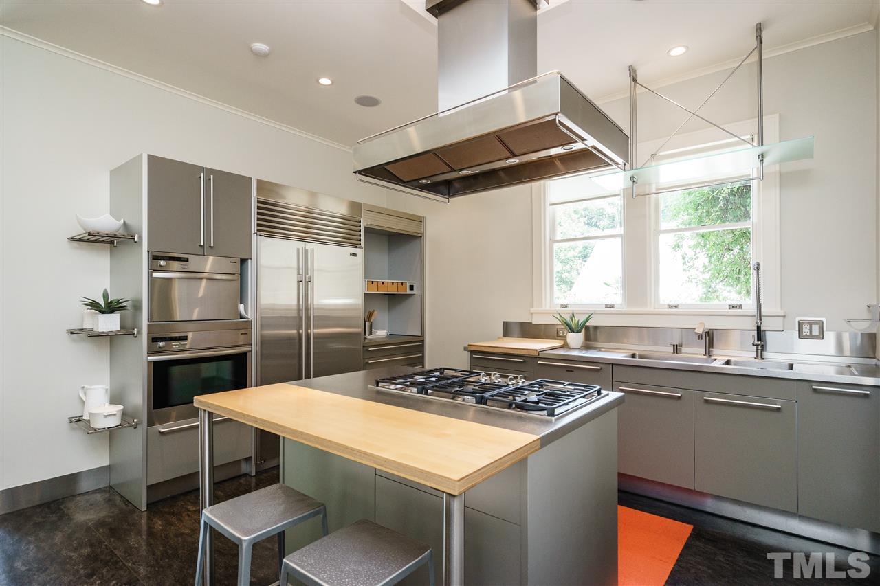 931 Vance Street Raleigh, NC 27608 - Photo 8 of 25 a kitchen with a sink a counter top space stainless steel appliances and a window