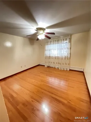 an empty room with wooden floor and fan