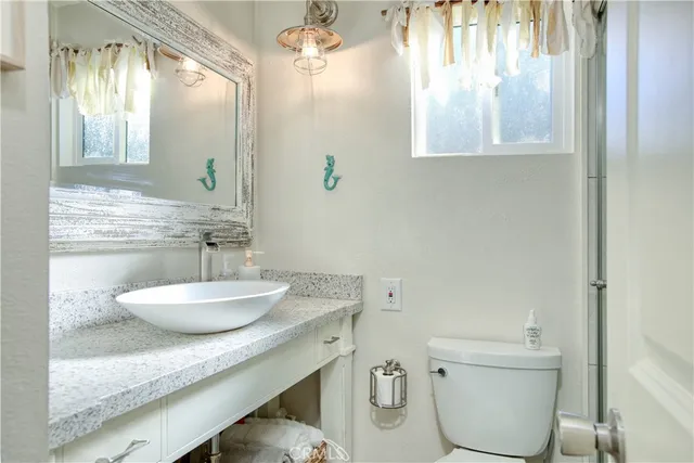 a bathroom with a granite countertop sink a toilet and a mirror