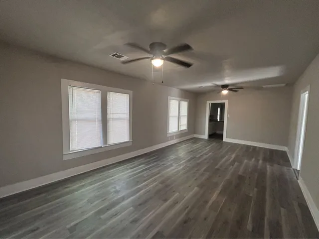 a view of empty room with wooden floor and fan