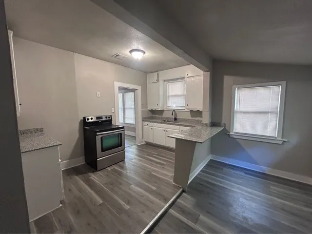 a large kitchen with a center island wooden floor and stainless steel appliances
