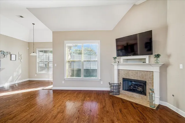 a view of an empty room with wooden floor fireplace and a window