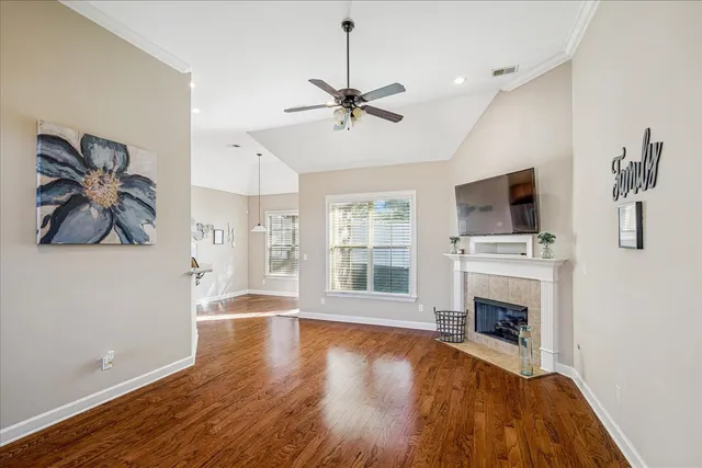 a view of a livingroom with a fireplace a ceiling fan and wooden floor