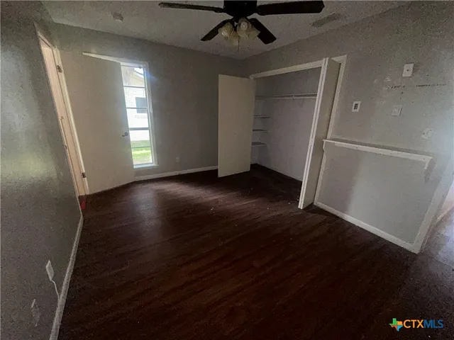 an empty room with wooden floor cabinet and windows