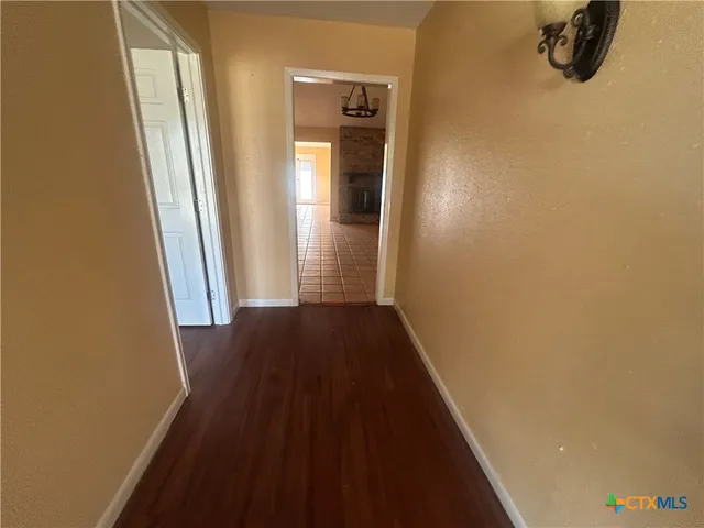 a view of a hallway with wooden floor and a bathroom