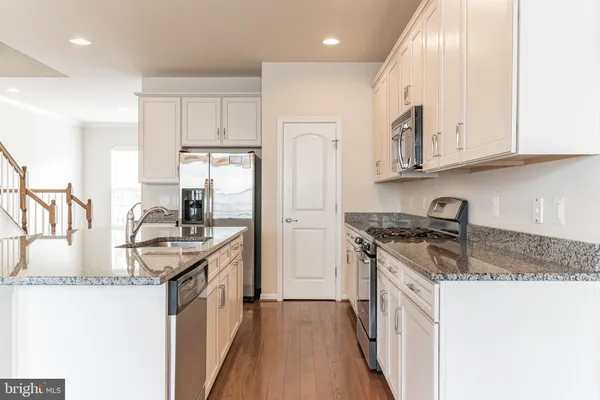 a kitchen with stainless steel appliances granite countertop a sink stove and cabinets