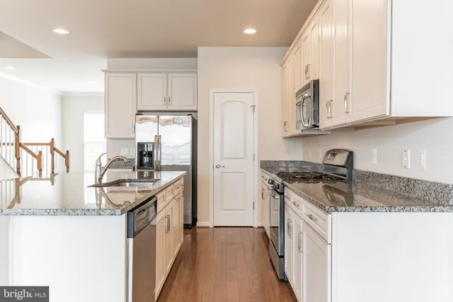 a kitchen with stainless steel appliances granite countertop a sink stove and cabinets