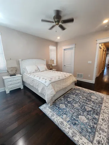 a bedroom with a bed and a dresser with wooden floor