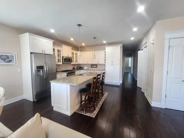 a kitchen with stainless steel appliances granite countertop a refrigerator a stove a sink dishwasher and a refrigerator with wooden floor