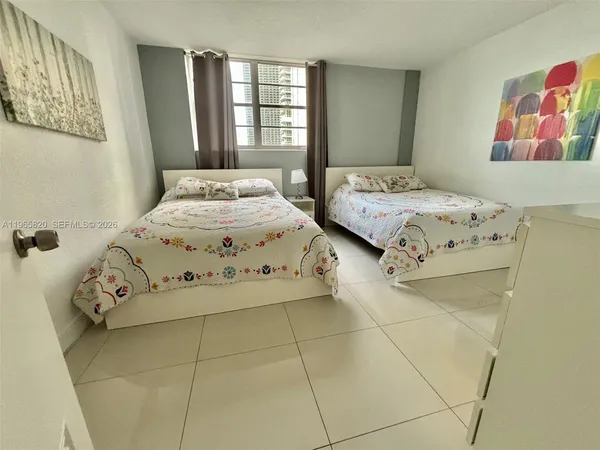 a bedroom with a bed next to a window and a flat screen tv