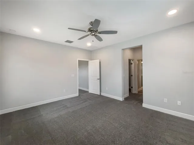 an empty room with closet and a ceiling fan