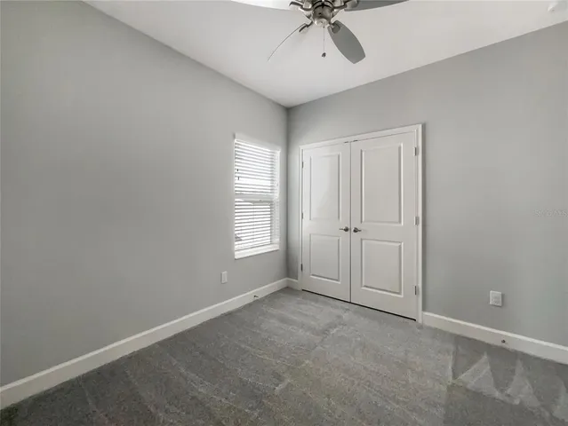 an empty room with a chandelier fan and windows