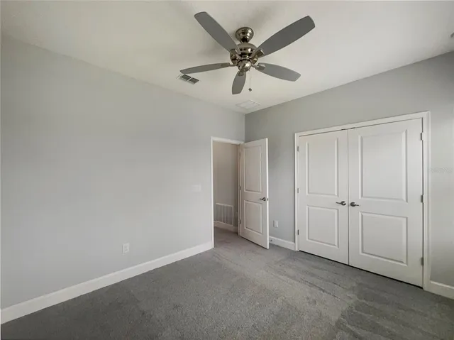 an empty room with closet and a chandelier fan