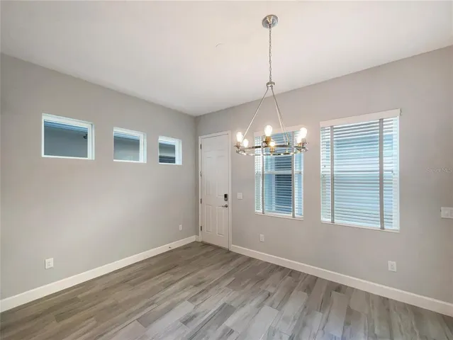 a view of a room with wooden floor chandelier and windows