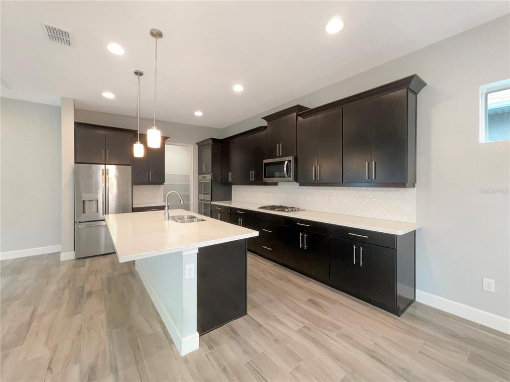 705 Winterside Drive Apollo Beach, FL 33572 - Photo 7 of 30 a large kitchen with stainless steel appliances kitchen island a large counter top and a wooden floors