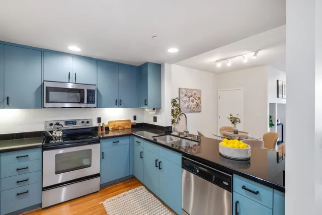 a kitchen with stainless steel appliances granite countertop a sink a stove oven a counter space and cabinets