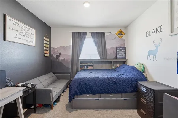 a bedroom with a bed a computer on the desk and a couch